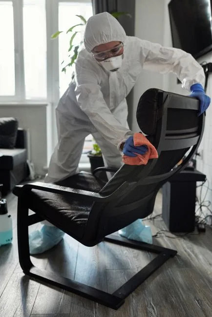 A man cleaning an indoor glass door with a spray bottle and cloth.